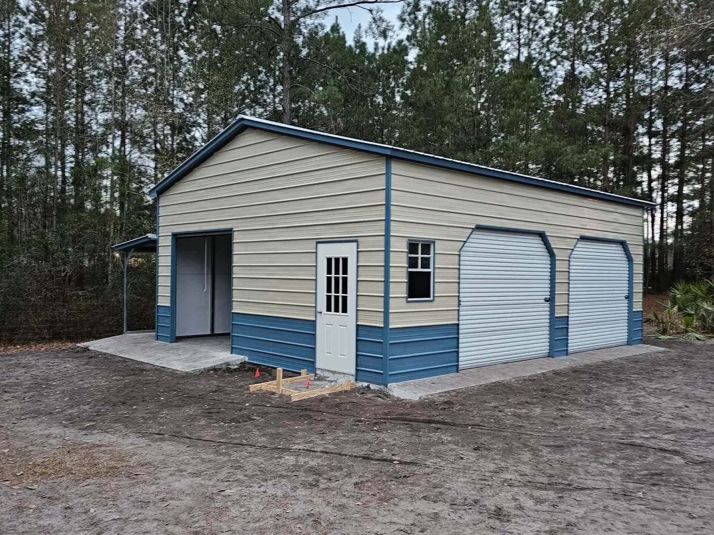 Cream steel garage with blue trim, two roll-up doors, and a side entrance