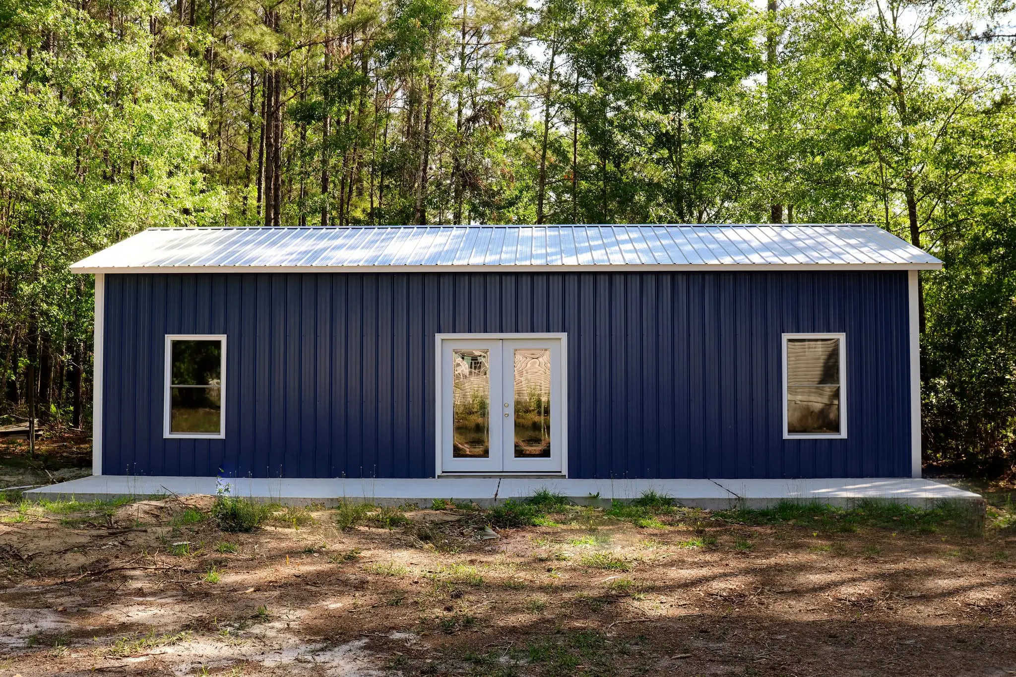Blue steel building with white double doors and windows