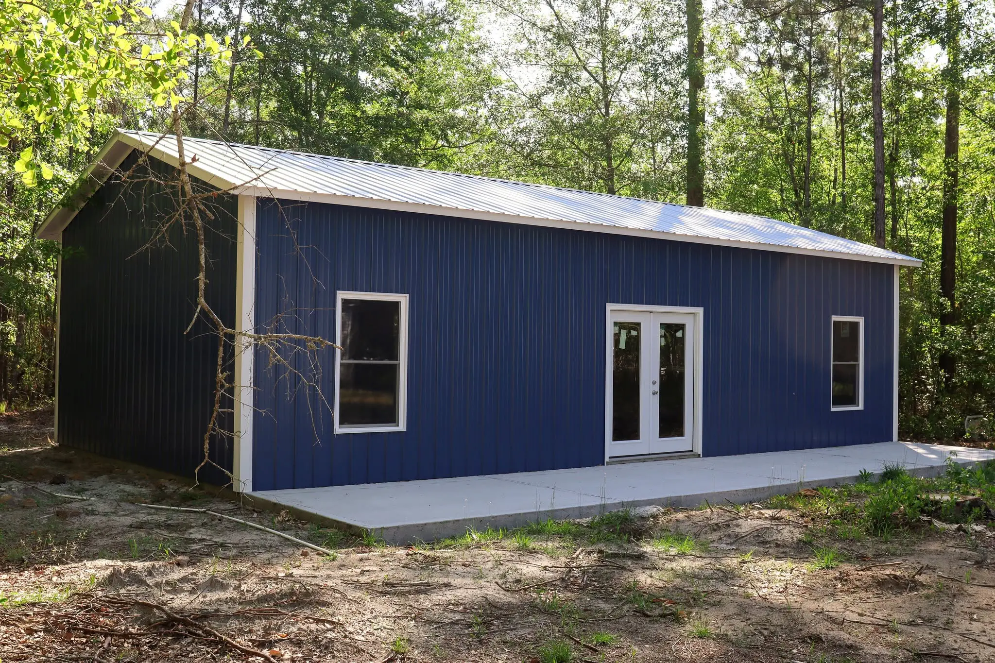 Angled view of a blue steel building with white doors and windows