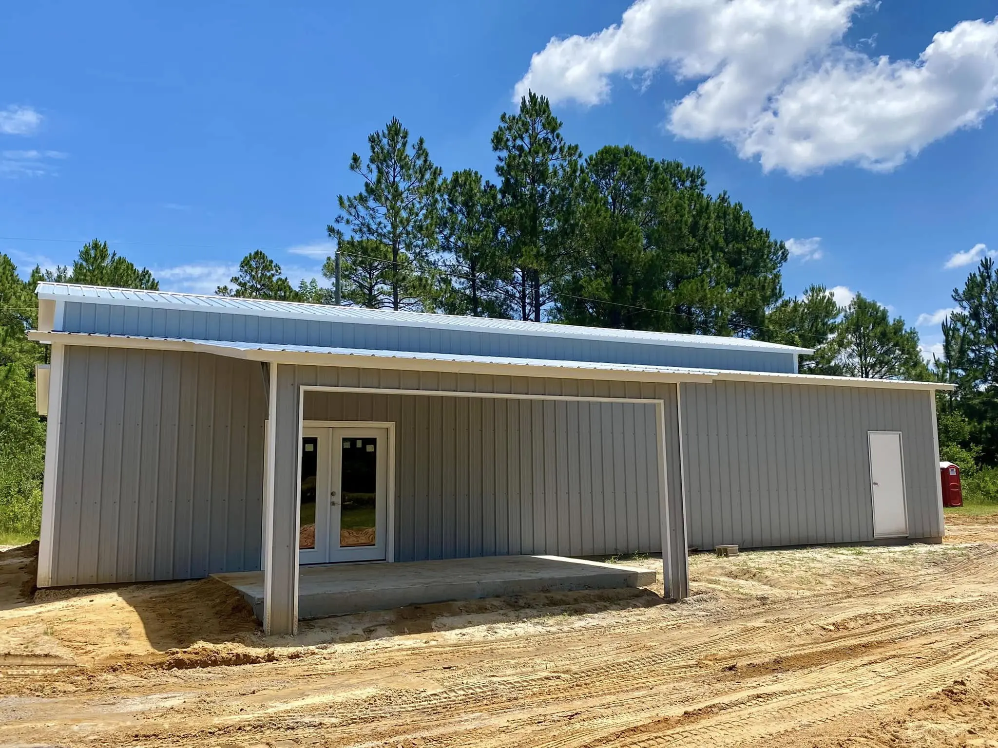 Gray steel building with a covered entrance and double doors
