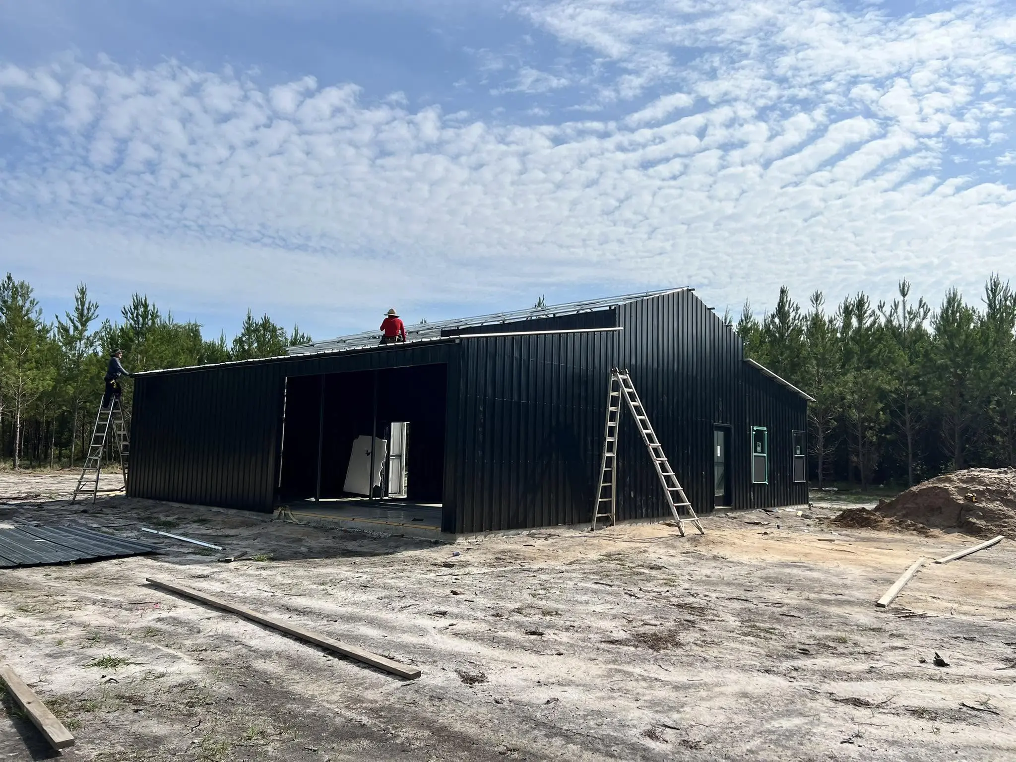 Crew installing roof panels on a black steel building