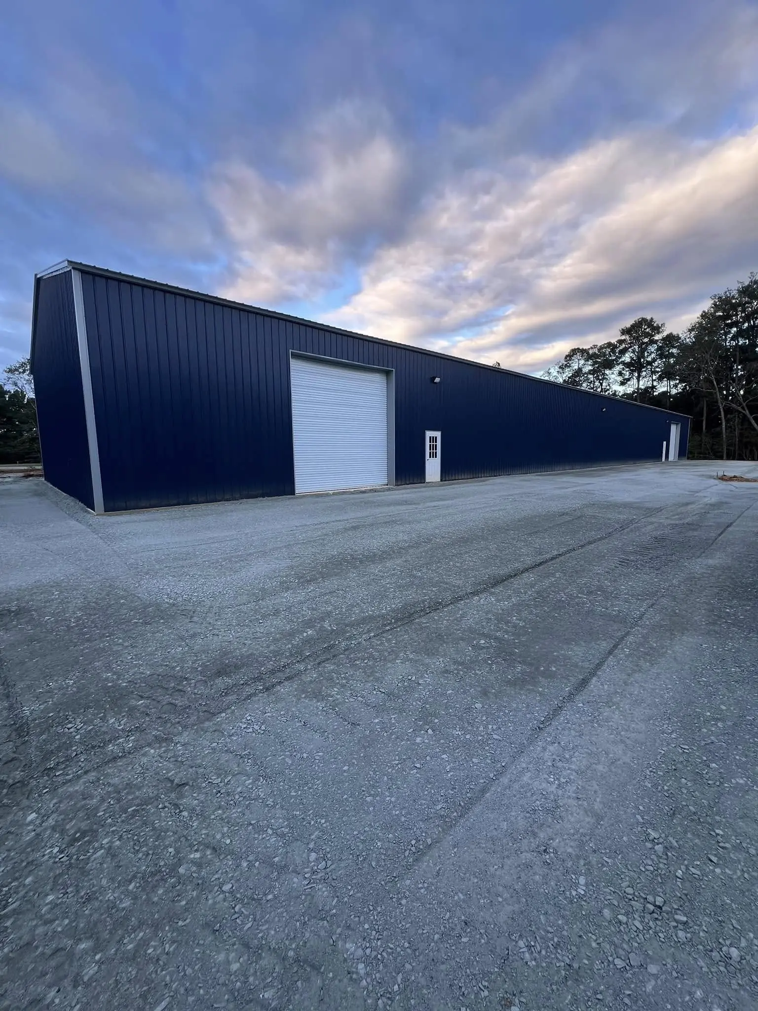 Long blue steel building with large white roll-up doors