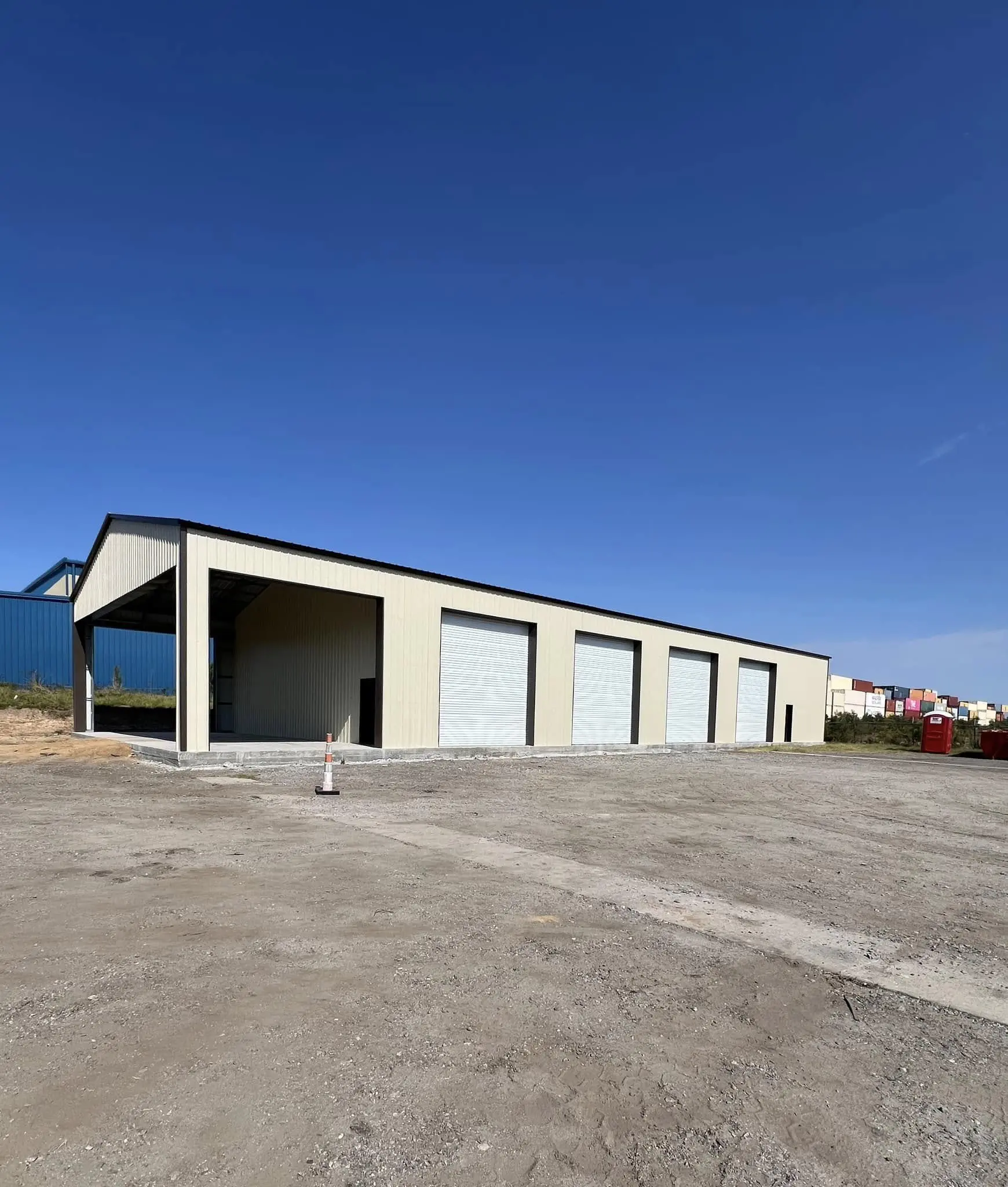Completed beige commercial building with four roll-up doors and an open end bay